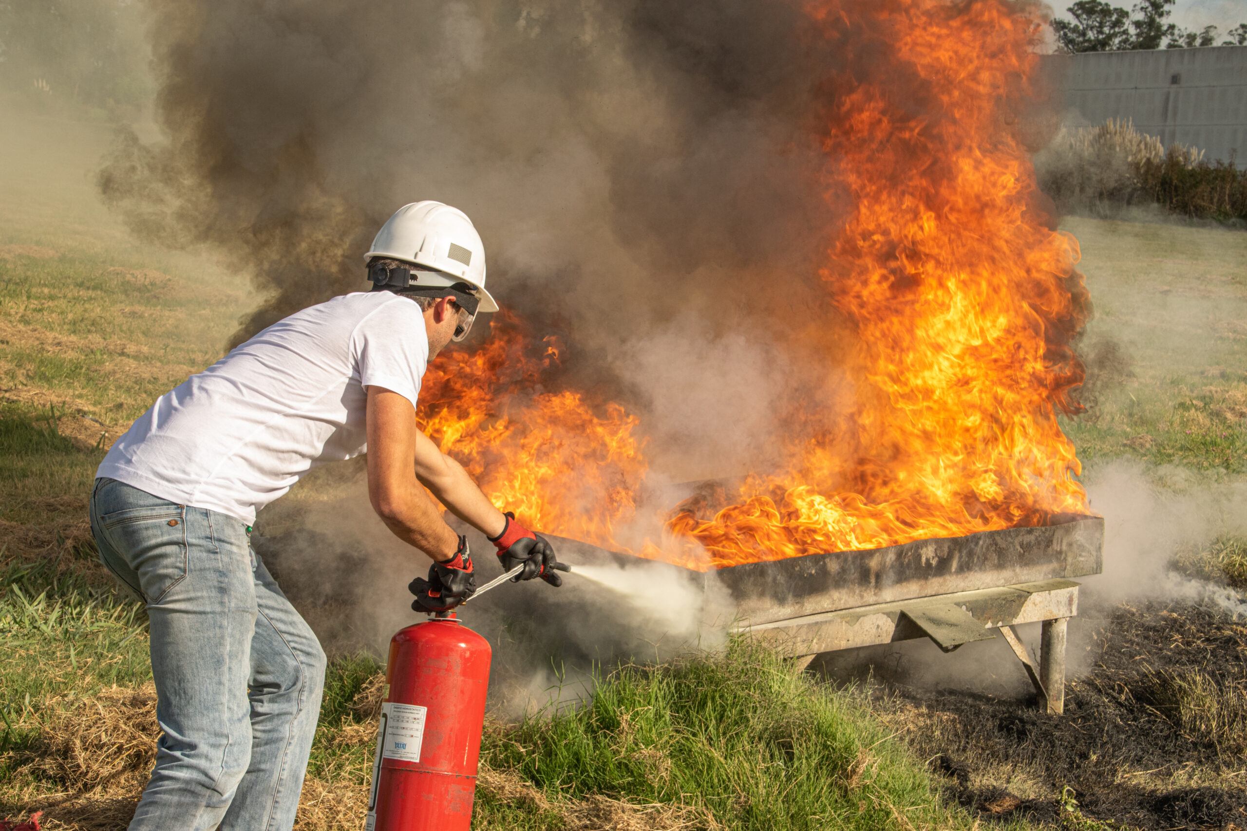 Salarié en formation Équipier Première Intervention manipulant un extincteur lors d'un exercice pratique de lutte incendie en intra-entreprise en Hauts-de-France